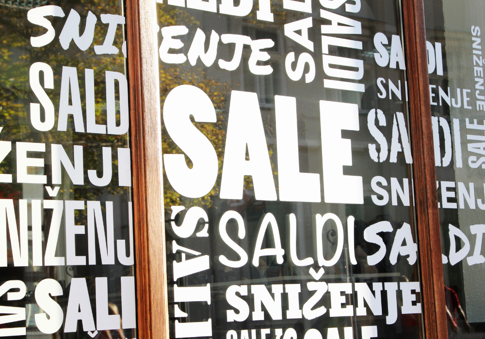 best sticker printing in Brisbane - image of shop front window covered in white sale stickers - call Infinite Print today